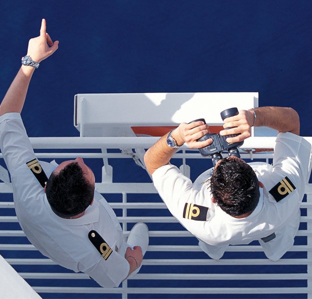 Two cruise ship officers observing the ocean and using binoculars | MSC Cruises