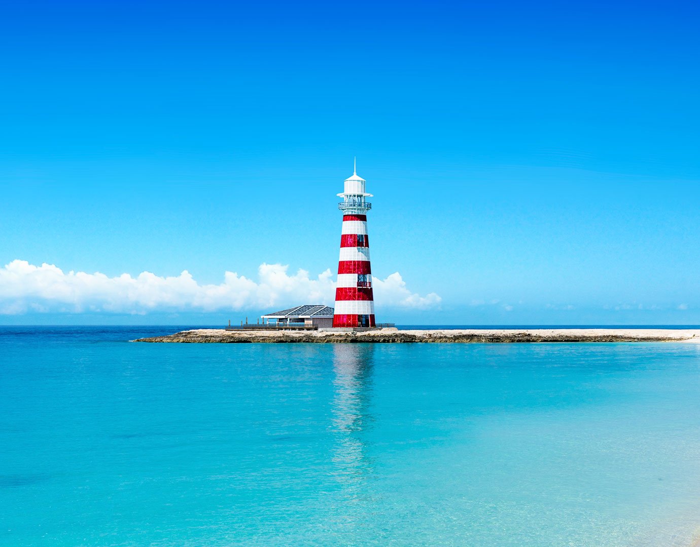 A red and white striped lighthouse on a pristine island with turquoise waters | MSC Cruises