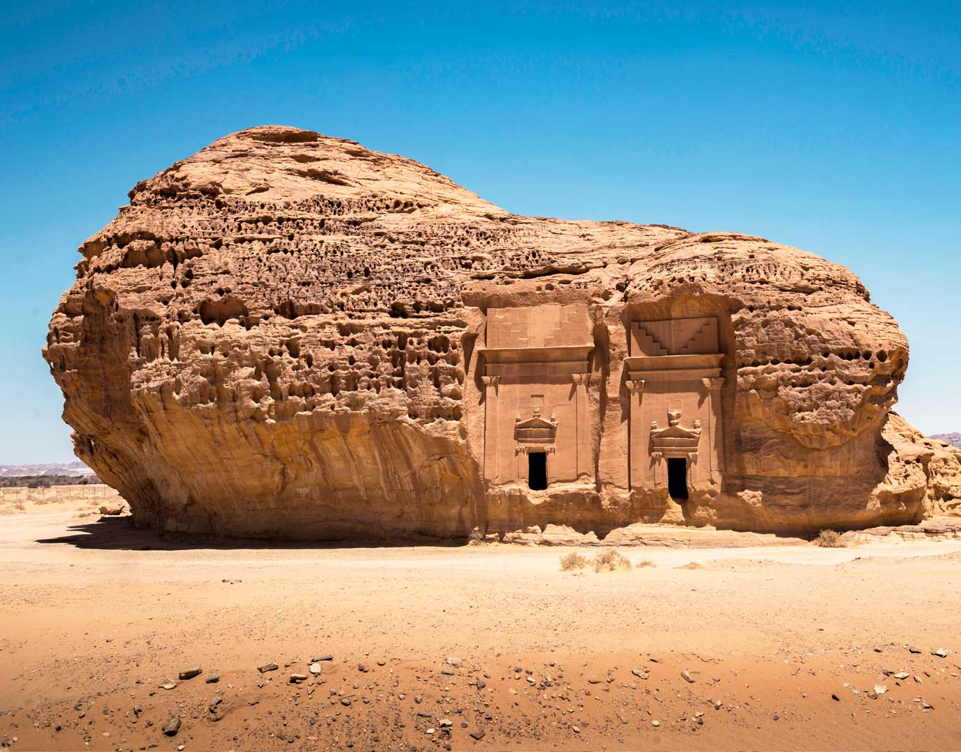 Ancient rock-carved tombs in a desert landscape under a clear blue sky | MSC Cruises