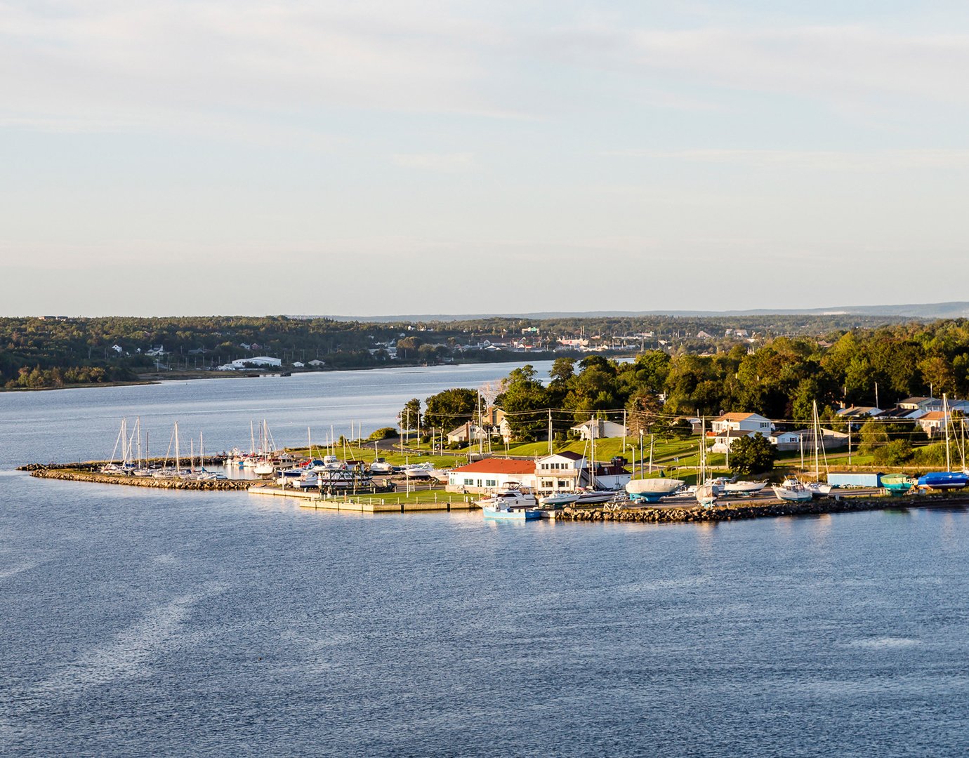 A scenic coastal town with a marina and sailboats, surrounded by lush greenery | MSC Cruises