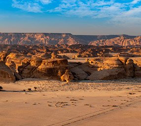 Golden desert landscape with rugged rock formations under a clear blue sky | MSC Cruises