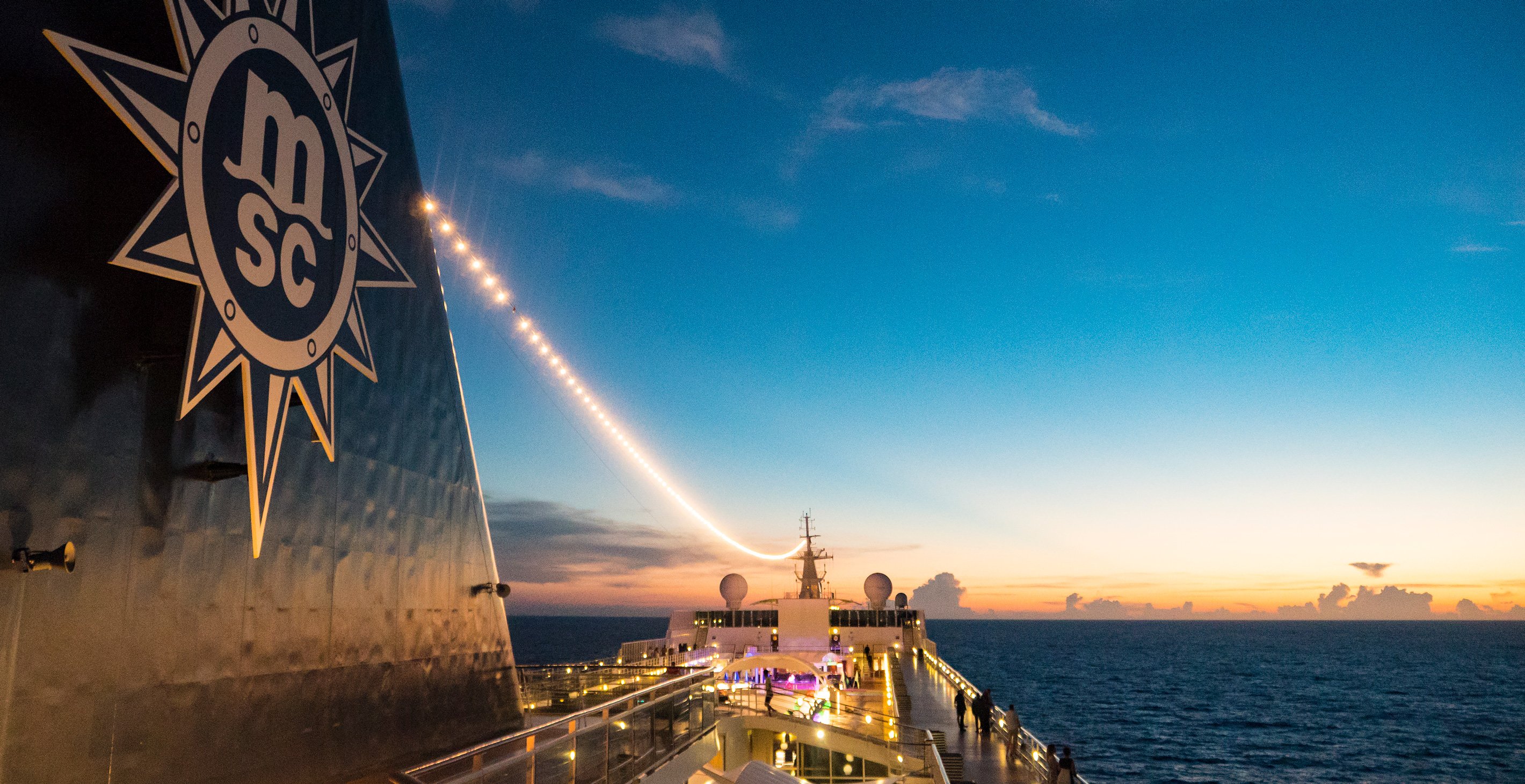 The deck of an MSC cruise ship illuminated at sunset over the ocean | MSC Cruises