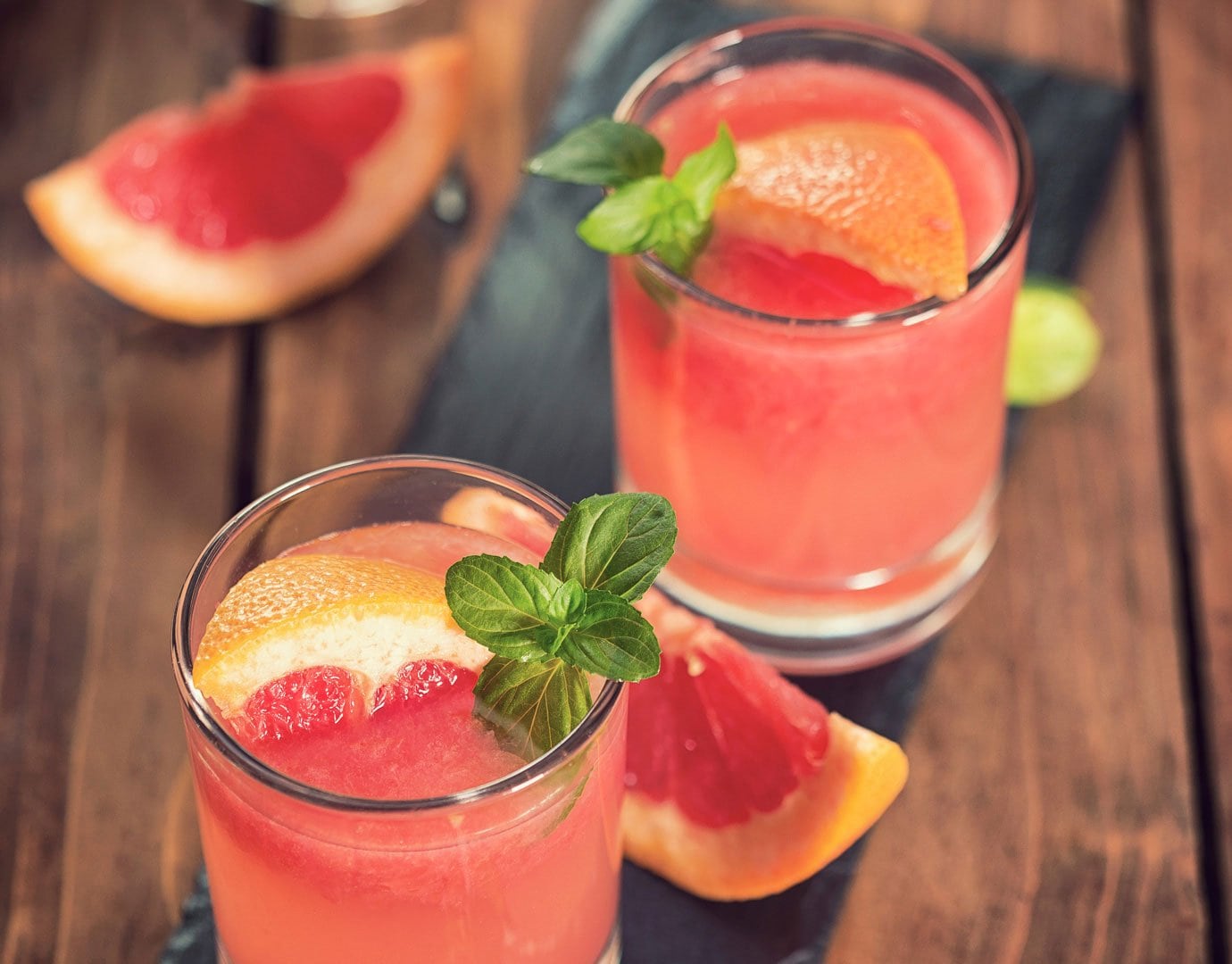 Refreshing grapefruit cocktails with mint garnish on a wooden table | MSC Cruises Refreshing grapefruit cocktails with mint garnish on a wooden table | MSC Cruises