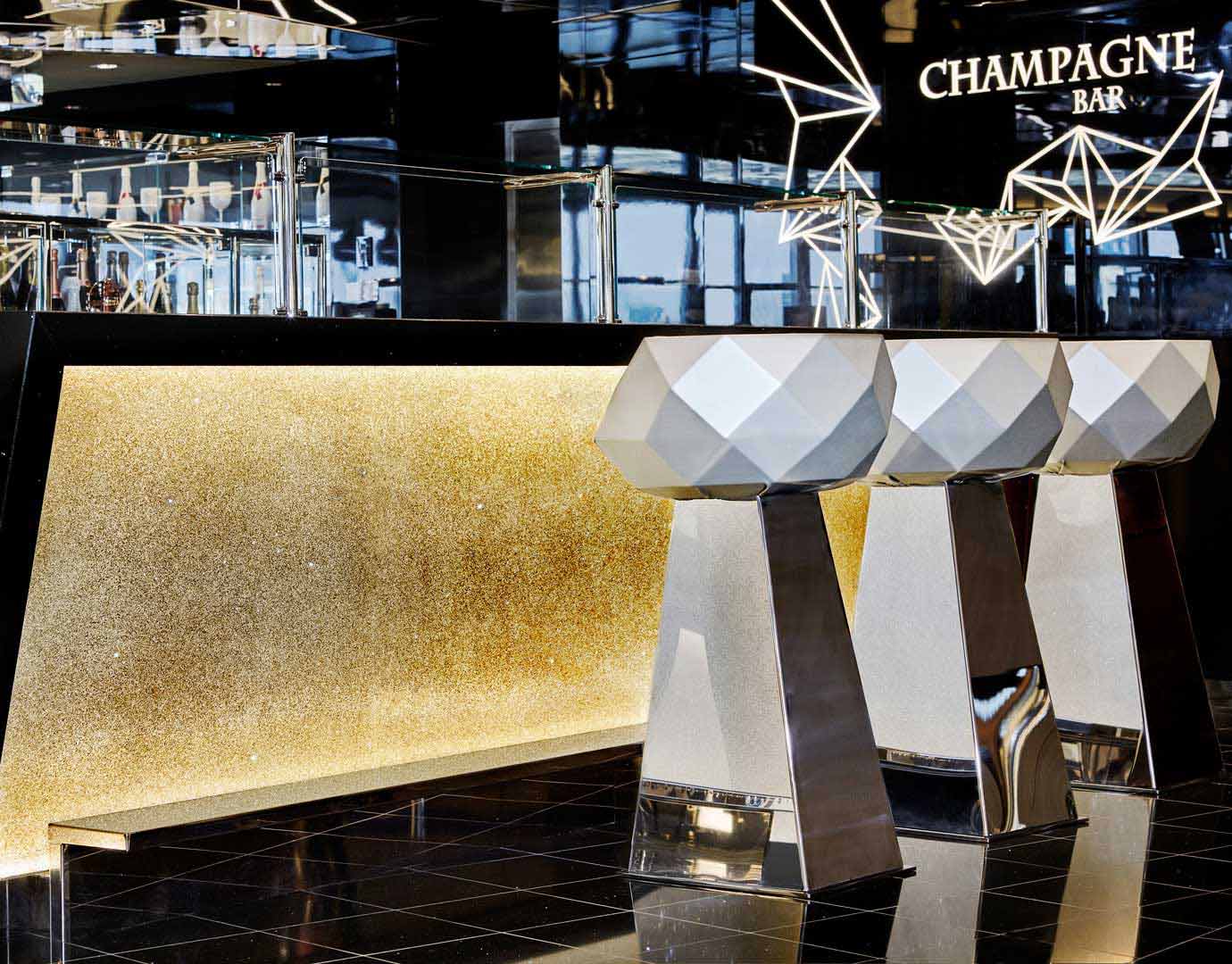 Luxurious champagne bar with geometric stools and golden accents onboard | MSC Cruises