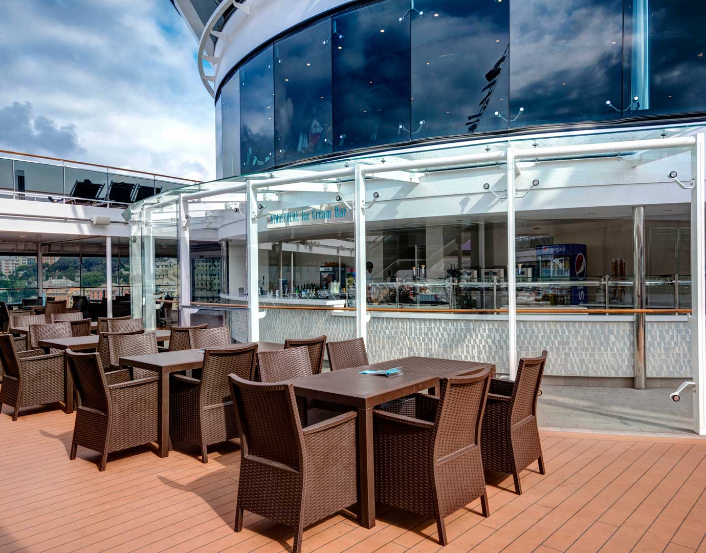 Outdoor seating area with wicker chairs and tables near an ice cream bar on an MSC cruise ship | MSC Cruises