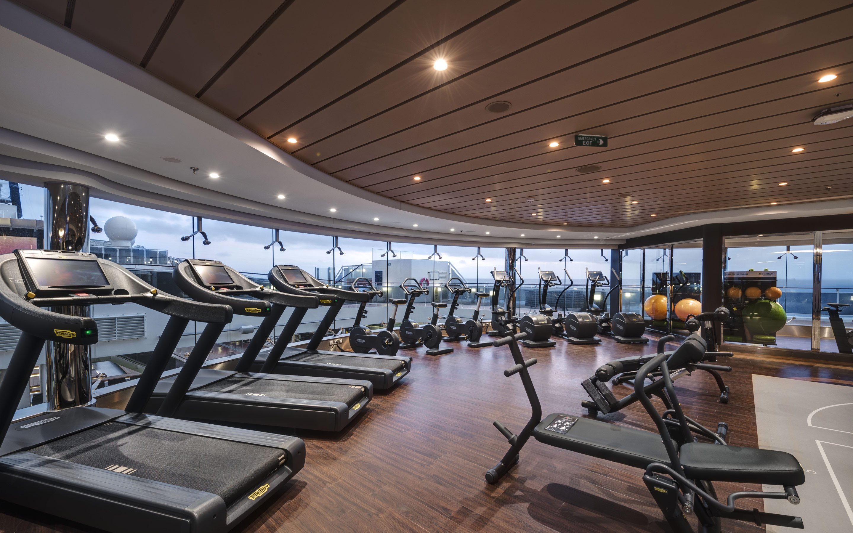 Modern fitness center with treadmills and exercise equipment overlooking the ocean | MSC Cruises Modern fitness center with treadmills and exercise equipment overlooking the ocean | MSC Cruises