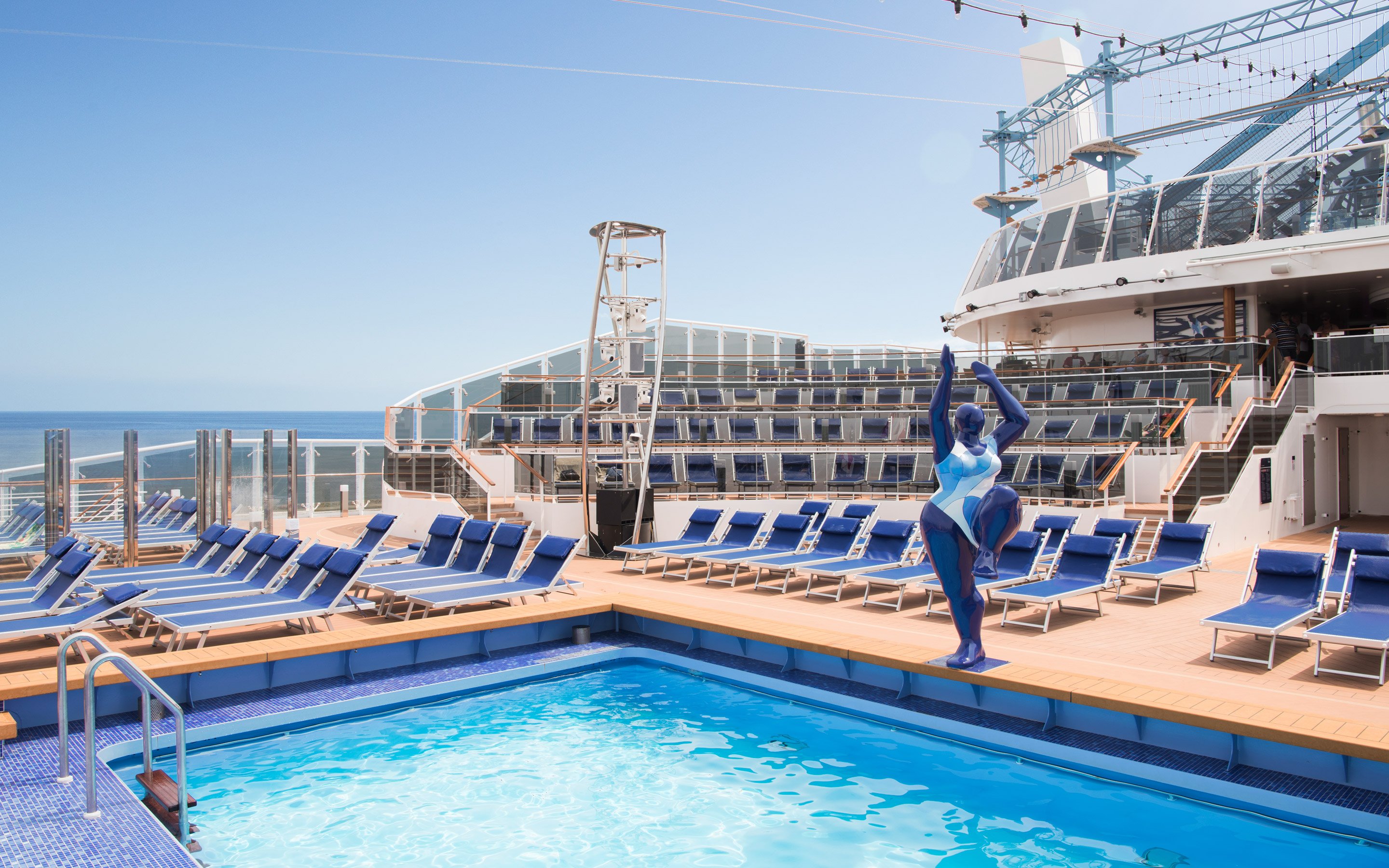 Sun deck with pool, lounge chairs, and modern sculpture on an MSC cruise ship | MSC Cruises Sun deck with pool, lounge chairs, and modern sculpture on an MSC cruise ship | MSC Cruises
