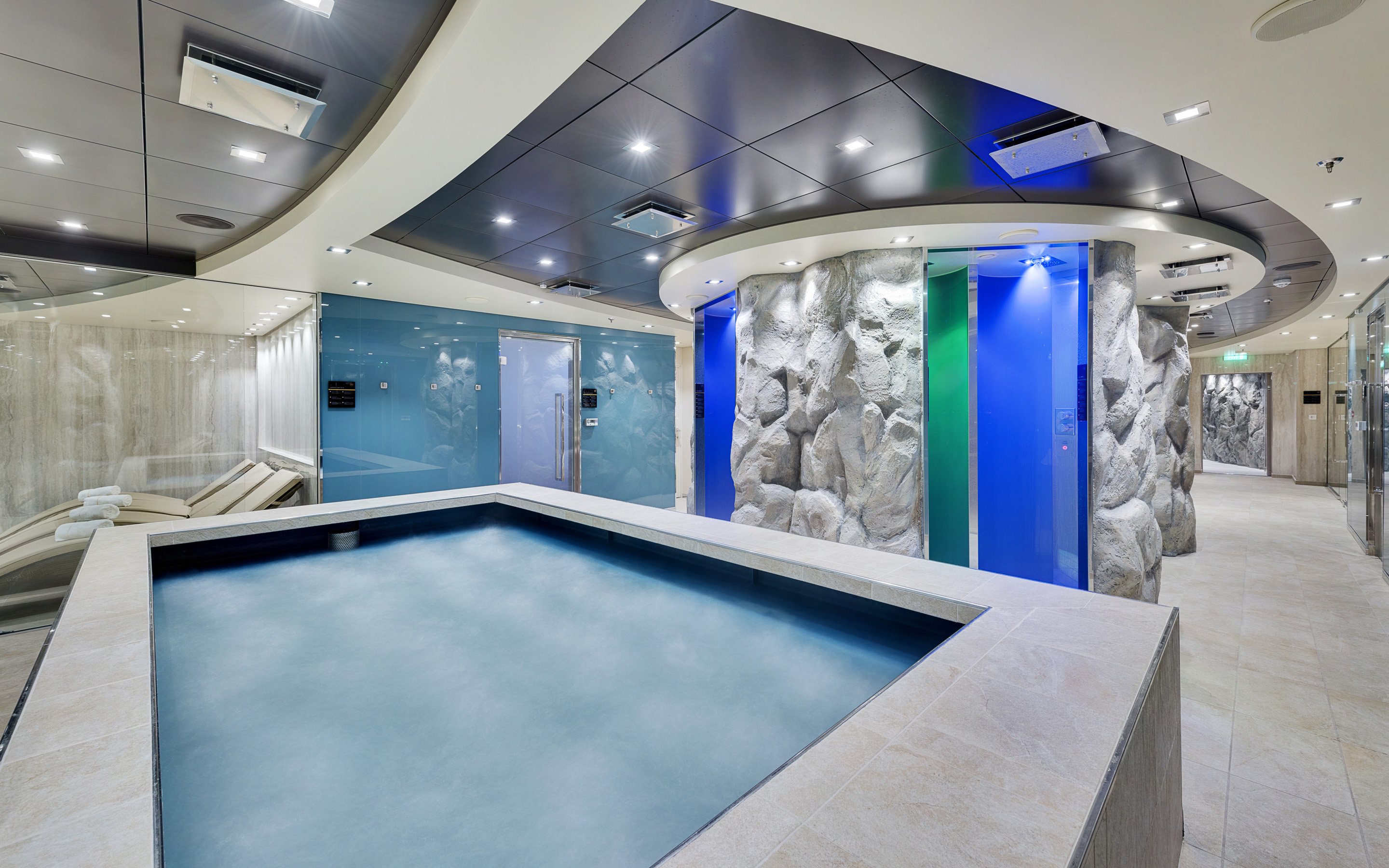 Luxurious spa area with a thermal pool, stone walls, and relaxation loungers onboard | MSC Cruises Luxurious spa area with a thermal pool, stone walls, and relaxation loungers onboard | MSC Cruises