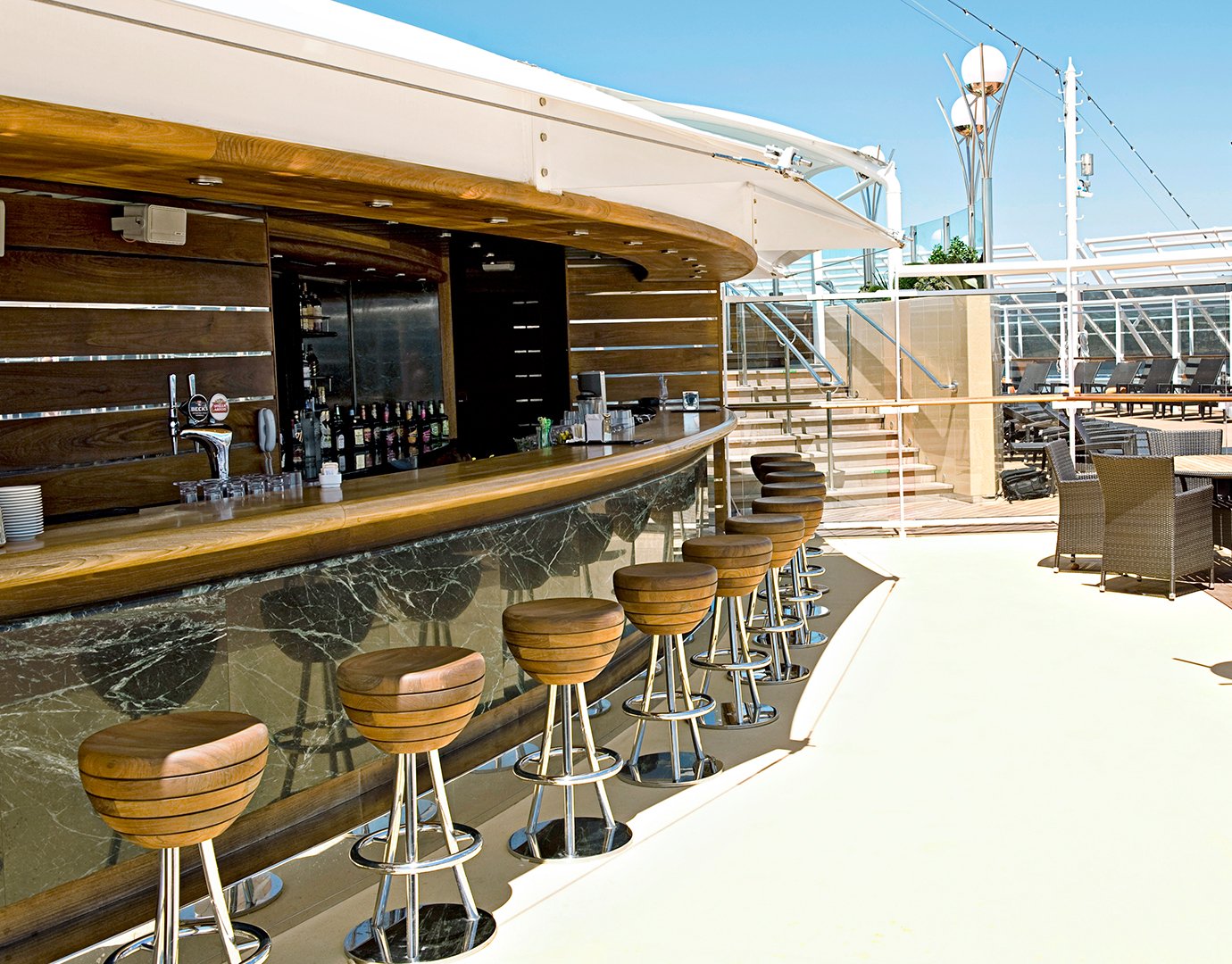 Outdoor bar with wooden stools and modern design on an MSC cruise ship deck | MSC Cruises Outdoor bar with wooden stools and modern design on an MSC cruise ship deck | MSC Cruises