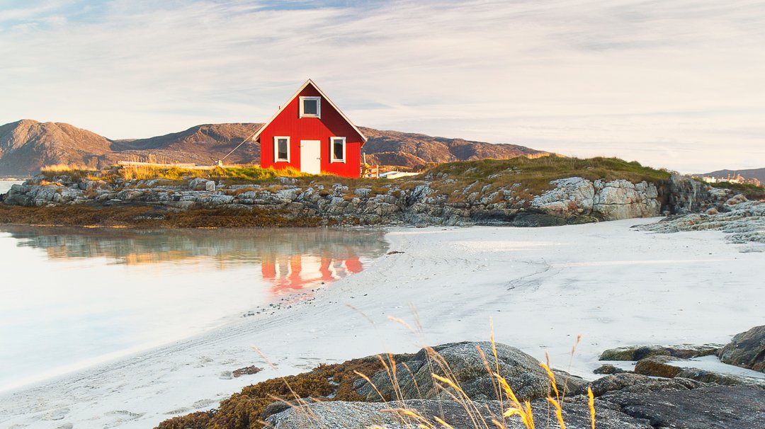 A red cabin on a rocky island with white sand and mountain views | MSC Cruises A red cabin on a rocky island with white sand and mountain views | MSC Cruises